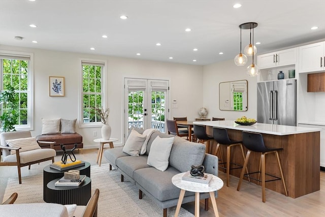 living area with recessed lighting, light wood-type flooring, french doors, and baseboards