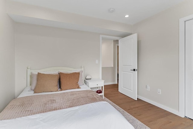 bedroom with wood finished floors, baseboards, and recessed lighting