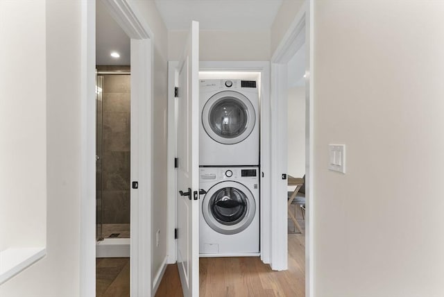 laundry area featuring stacked washing machine and dryer and wood finished floors