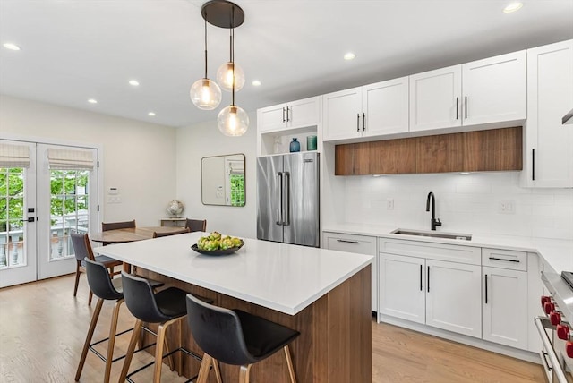 kitchen featuring premium appliances, a sink, light wood finished floors, light countertops, and recessed lighting