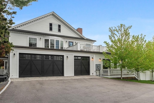 view of front of property with driveway, a chimney, a balcony, and central air condition unit