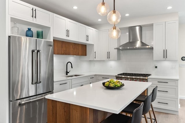 kitchen with stainless steel appliances, wall chimney range hood, a sink, open shelves, and light countertops