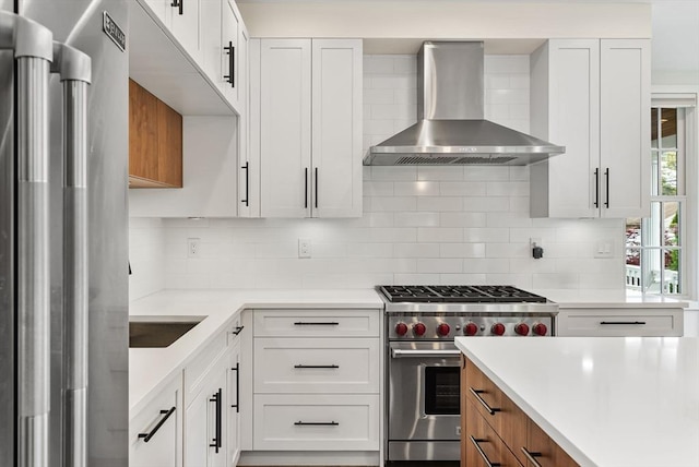 kitchen featuring wall chimney exhaust hood, appliances with stainless steel finishes, light countertops, and tasteful backsplash