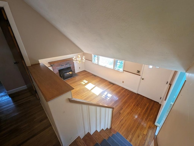 bonus room with wood finished floors, visible vents, vaulted ceiling, a textured ceiling, and a chandelier