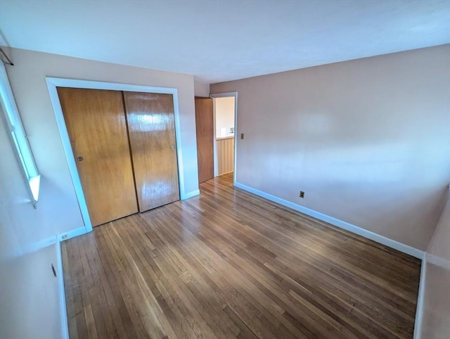 unfurnished bedroom with a closet, baseboards, and wood finished floors