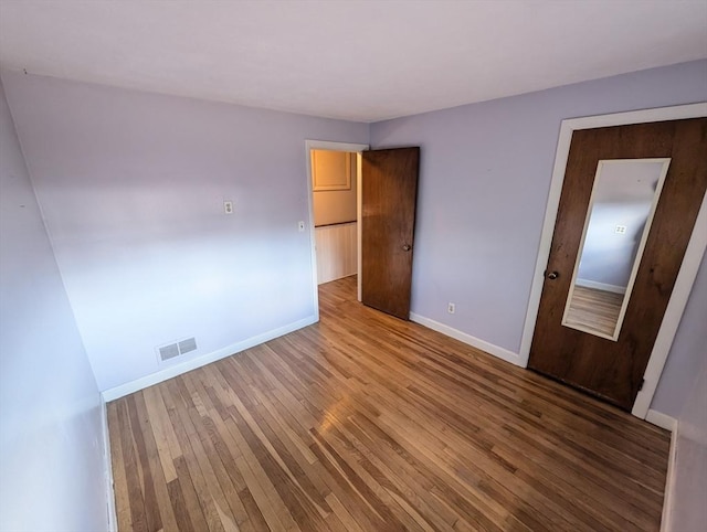 unfurnished bedroom with baseboards, visible vents, and wood-type flooring