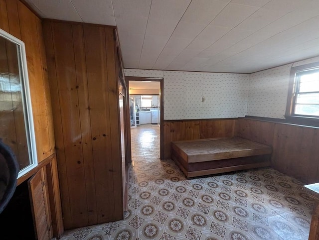 hall featuring wallpapered walls, wooden walls, and wainscoting