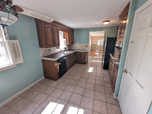 kitchen featuring tasteful backsplash, freestanding refrigerator, light tile patterned flooring, light countertops, and dishwasher