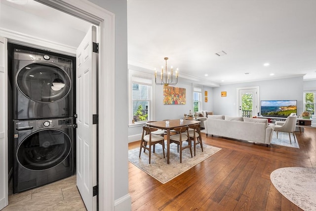 202 Middlesex Ave Unit 2, Medford, MA 02155 - laundry room with stacked washer and clothes dryer, a chandelier, ornamental molding, healthy amount of natural light, and wood-type flooring