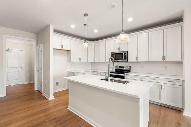 kitchen with a center island with sink, sink, white cabinetry, and stainless steel appliances