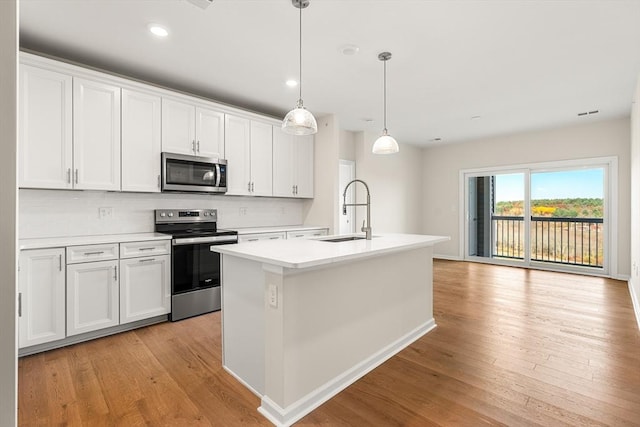 kitchen with a kitchen island with sink, white cabinetry, sink, and appliances with stainless steel finishes