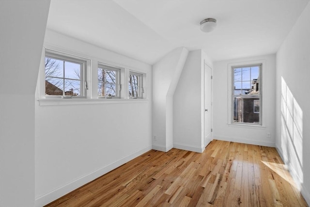 additional living space featuring light wood-type flooring and lofted ceiling