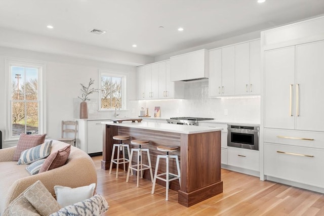 60 Williams St Unit 402, Boston, MA 02130 - kitchen featuring a kitchen bar, a kitchen island, tasteful backsplash, light wood-style flooring, and recessed lighting
