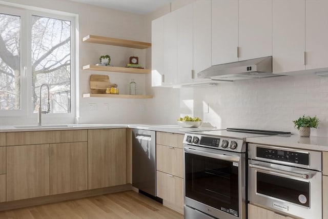 kitchen featuring sink, appliances with stainless steel finishes, white cabinetry, light brown cabinetry, and light wood-type flooring