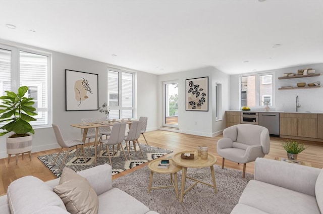 living room featuring sink, light hardwood / wood-style flooring, and a healthy amount of sunlight