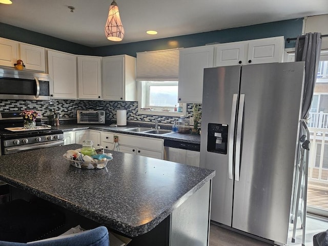 kitchen with a sink, backsplash, dark countertops, and appliances with stainless steel finishes