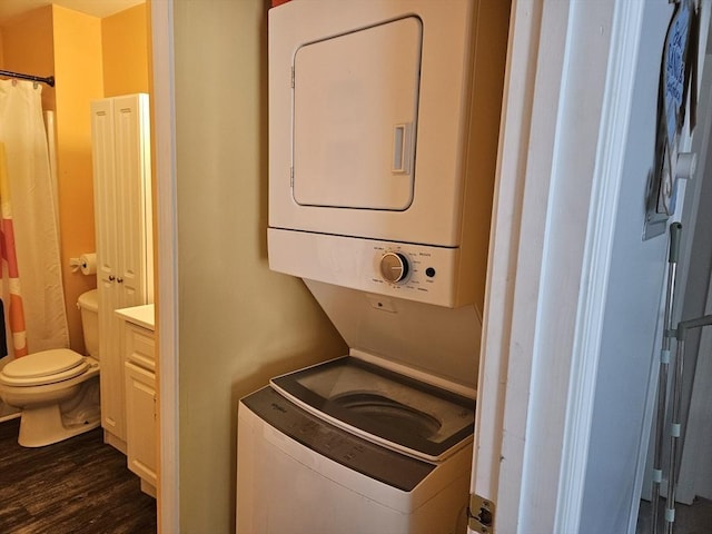 laundry room with stacked washer and clothes dryer, dark wood finished floors, and laundry area