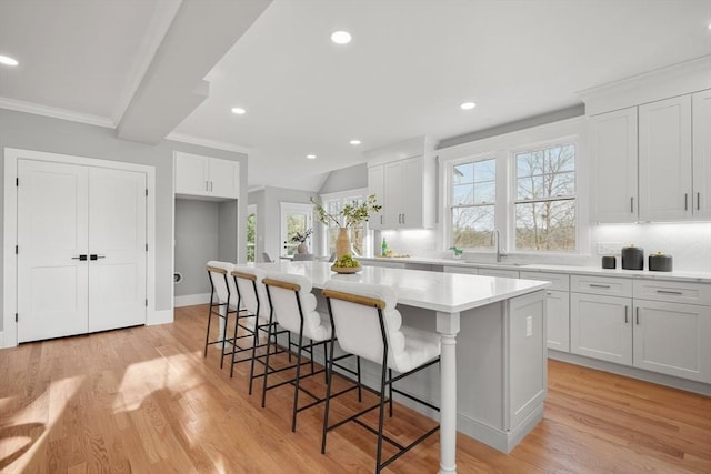 kitchen with light hardwood / wood-style floors, a center island, white cabinetry, and a breakfast bar area