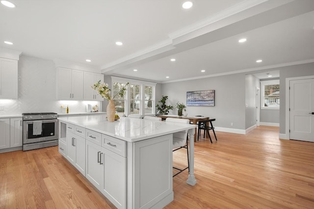 kitchen featuring stainless steel range with gas cooktop, a center island, white cabinets, and ornamental molding