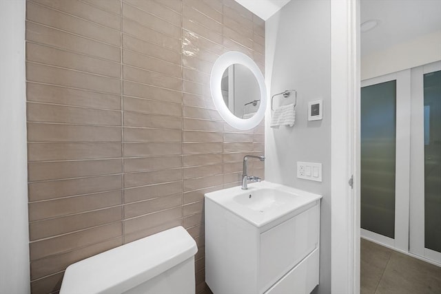 25 Day St, Newton, MA 02466 - half bathroom with tile walls, toilet, vanity, and tile patterned flooring