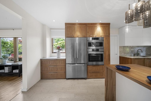 25 Day St, Newton, MA 02466 - kitchen featuring appliances with stainless steel finishes, brown cabinetry, tasteful backsplash, a sink, and recessed lighting