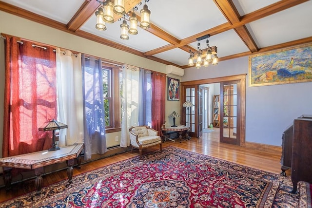 sitting room with a wall mounted AC, wood finished floors, a notable chandelier, and french doors