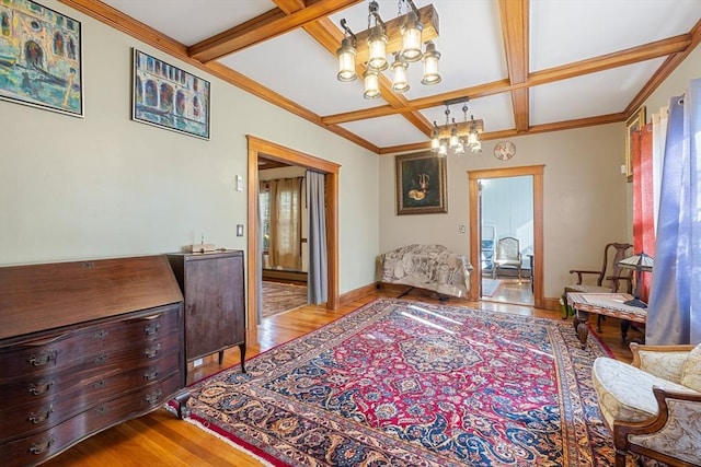 living area with a healthy amount of sunlight, light wood-style floors, a chandelier, and coffered ceiling