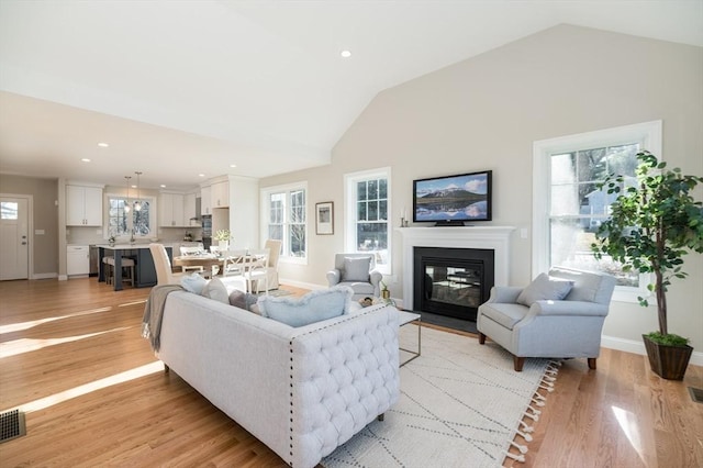 62 High St Lot 6, Stoneham, MA 02180 - living area with a glass covered fireplace, vaulted ceiling, baseboards, light wood-type flooring, and recessed lighting