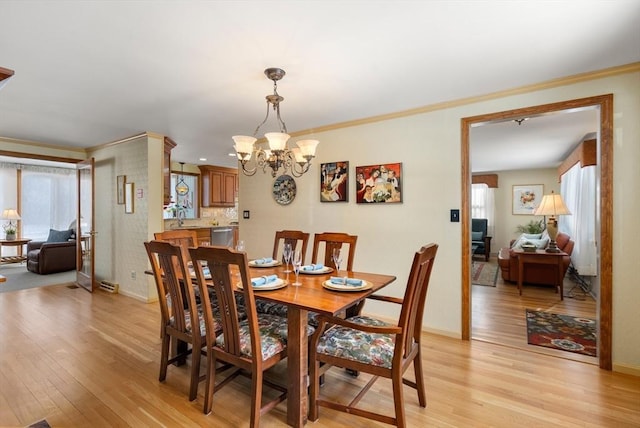 dining room featuring ornamental molding, an inviting chandelier, and light wood-type flooring