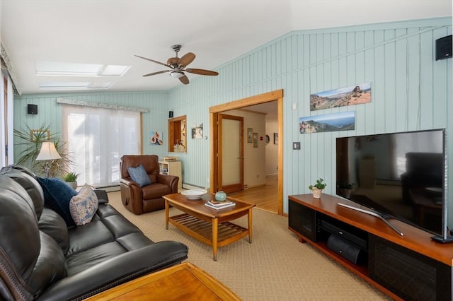 living room with carpet flooring, vaulted ceiling with skylight, and ceiling fan