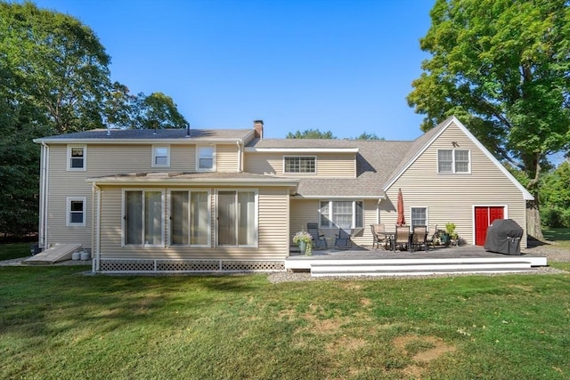 rear view of house featuring a wooden deck and a lawn