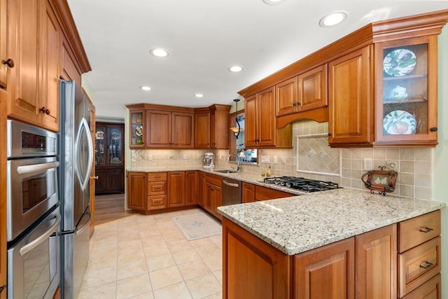 kitchen with light stone countertops, appliances with stainless steel finishes, sink, and decorative backsplash