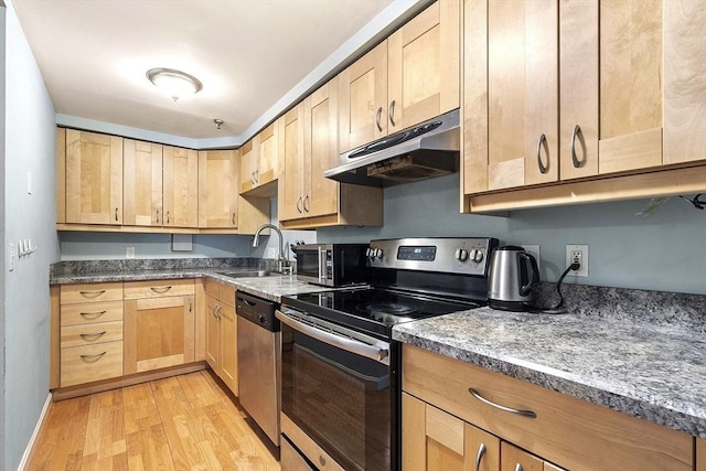 kitchen featuring stainless steel appliances, sink, light brown cabinets, dark stone countertops, and light hardwood / wood-style floors