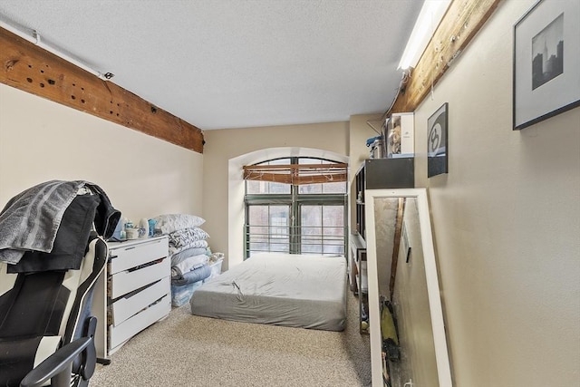 carpeted bedroom featuring a textured ceiling and beamed ceiling