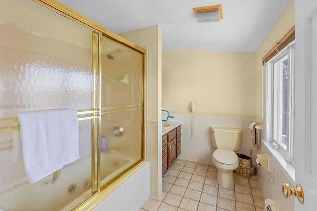 full bathroom featuring bath / shower combo with glass door, tile walls, tile patterned flooring, vanity, and toilet