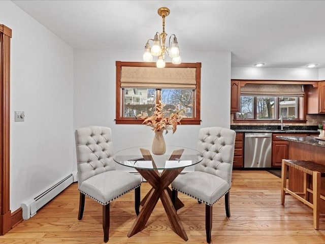 dining area featuring a baseboard radiator, light wood-style flooring, and a notable chandelier