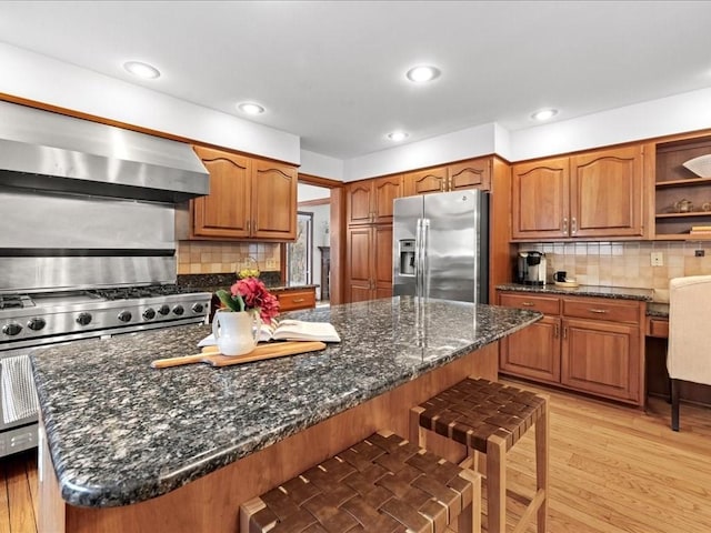 kitchen with a breakfast bar area, extractor fan, stainless steel appliances, open shelves, and brown cabinetry