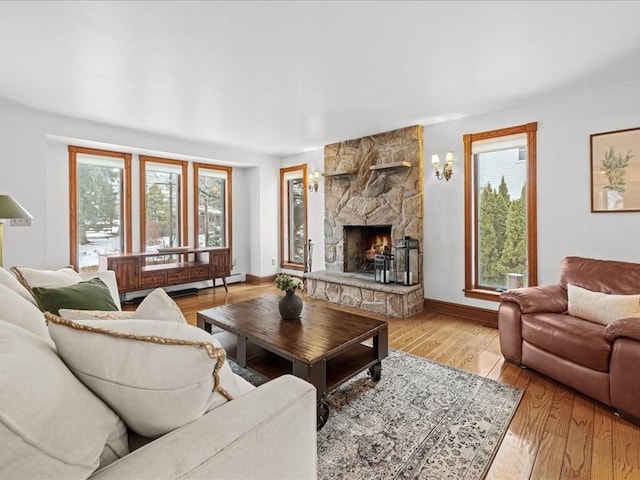 living area featuring a baseboard radiator, a fireplace, light wood-style flooring, and baseboards