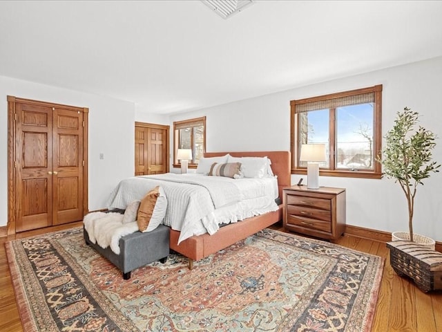 bedroom featuring visible vents, baseboards, and wood finished floors