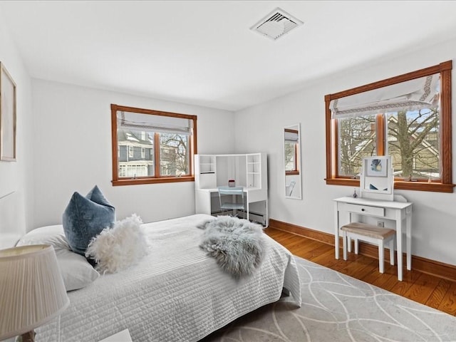 bedroom featuring wood finished floors, visible vents, and baseboards