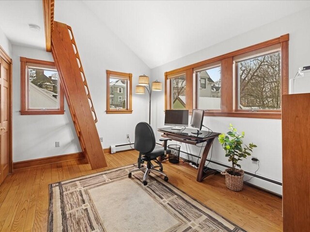 office featuring lofted ceiling, baseboard heating, baseboards, and light wood-style floors