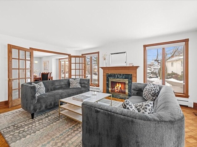 living room featuring a baseboard radiator, baseboards, and a premium fireplace