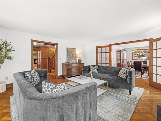 living area featuring a notable chandelier, stairway, and baseboards