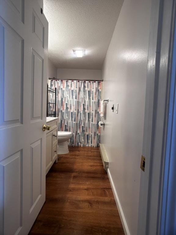 bathroom with wood-type flooring, vanity, toilet, a textured ceiling, and a shower with shower curtain