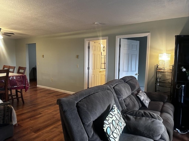 living room featuring ceiling fan, dark hardwood / wood-style floors, and a textured ceiling