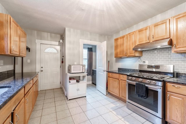 71 Daviston St, Springfield, MA 01108 - kitchen featuring gas range, under cabinet range hood, white microwave, light tile patterned floors, and decorative backsplash