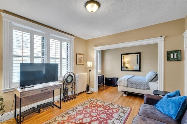 bedroom featuring hardwood / wood-style floors, radiator heating unit, and a textured ceiling