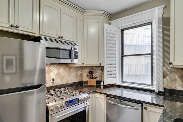 kitchen featuring tasteful backsplash, stainless steel appliances, cream cabinets, and dark stone counters