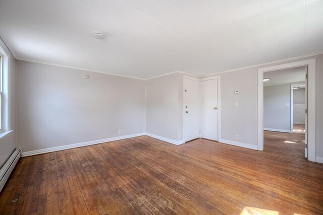 spare room with hardwood / wood-style flooring, a baseboard heating unit, baseboards, crown molding, and a smoke detector