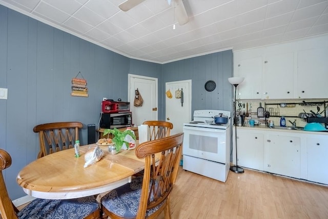 kitchen with white electric stove, stainless steel microwave, light wood-type flooring, and white cabinets